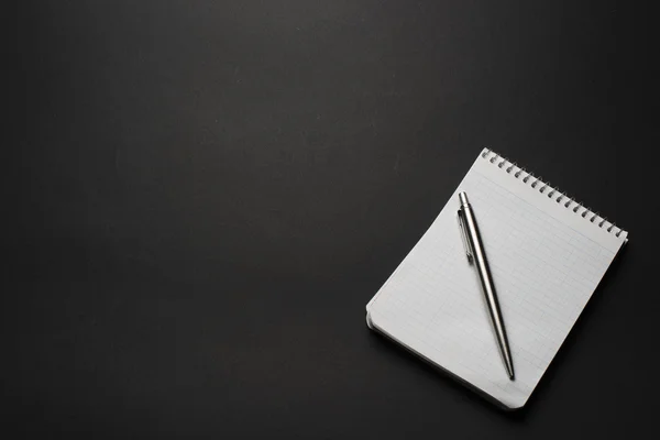 Блокнот і ручка на чорному столі — стокове фото