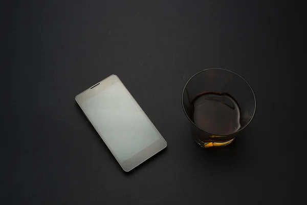 Smartphone och cognac på ett svart bord Royaltyfria Stockbilder