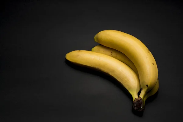 Trzy banany na ciemnym tle — Zdjęcie stockowe