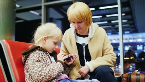 Мати і дочка чекали на літак і грали на вашому телефоні — стокове відео