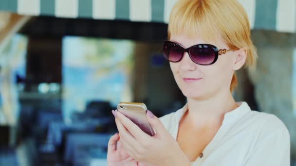 Жінка-туристка використовує мобільний телефон на фоні вікна магазину — стокове відео