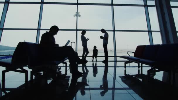 Familia esperando un vuelo, utiliza un dispositivo electrónico diferente — Vídeos de Stock