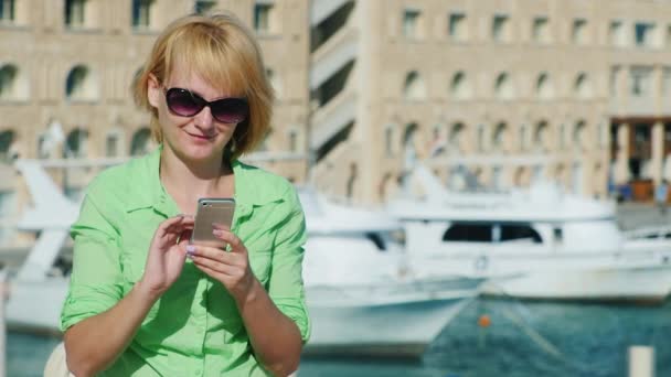 Woman typing sms on a tourist city skyline with yachts — Stock Video