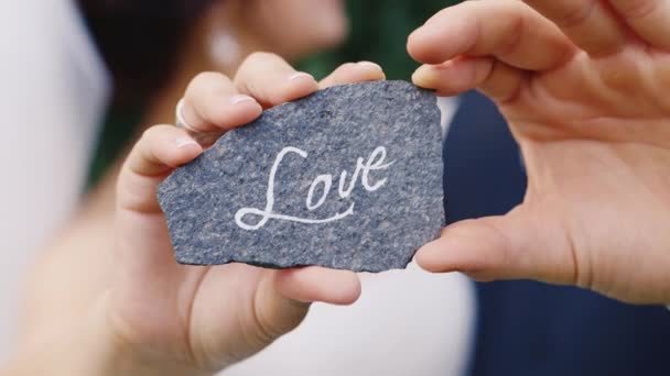 Una pietra con un'iscrizione Amore nelle mani di una coppia amorevole — Video Stock