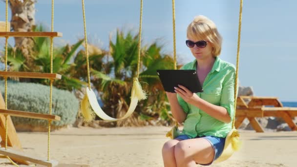 Vrouw zitten op een schommel en geniet van de Tablet PC — Stockvideo