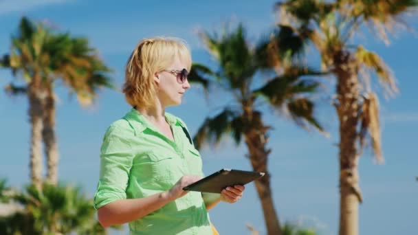 Um turista olha para o caminho a partir do mapa no tablet — Vídeo de Stock