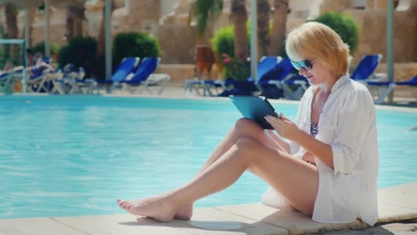 Frau entspannt sich am Pool, genießt die Tablette — Stockvideo