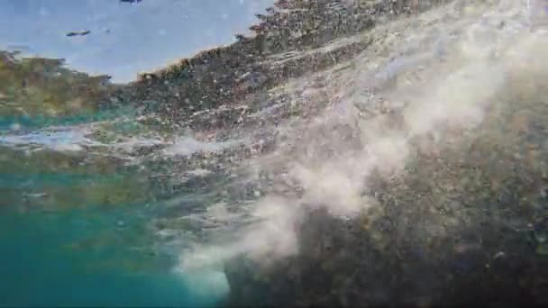 冲浪在水之下，海浪拍打在岩石上 — 图库视频影像