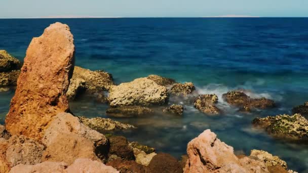 Sörf kayalar - kırmızı, mavi deniz bir arka plan üzerinde taş — Stok video