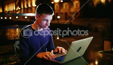 Genç bir dizüstü bilgisayar gece geç saatlerde kullanır.