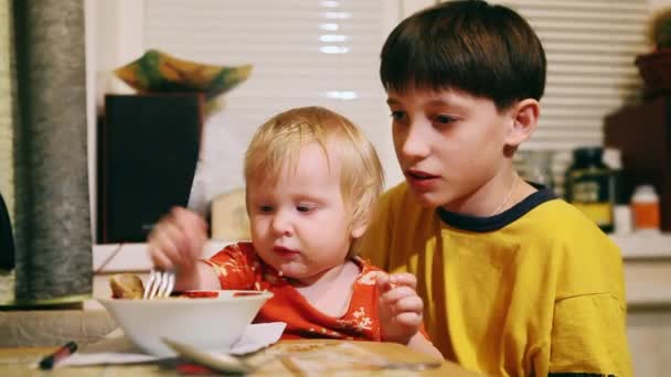 Vicces 5-6 hónapos kislány eszik egy csirkecomb. Kipróbálás-hoz táplál a bátyja — Stock videók