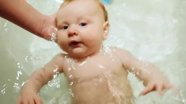 Новорожденная девочка купается в ванне — стоковое видео