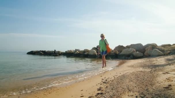 Een toerist in de zomer kleding gaat blote voeten op het water — Stockvideo