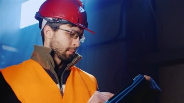 Genç bir adam bir kask ve tulum tablet kullanır