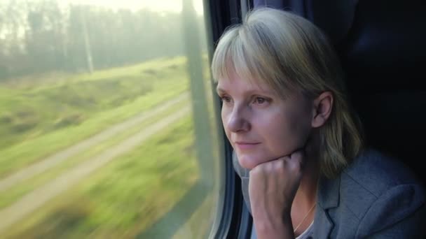 Mujer reflexiva mirando por la ventana de un tren que viaja — Vídeos de Stock