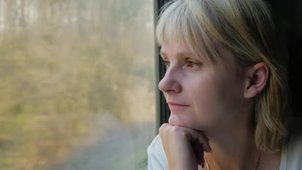 Портрет молодой задумчивой женщины, смотрящей в окно поезда — стоковое видео