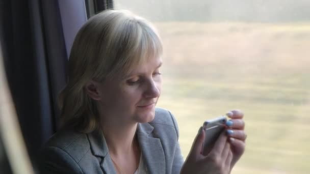 Jonge vrouw genieten van een telefoon bij een trein-venster — Stockvideo