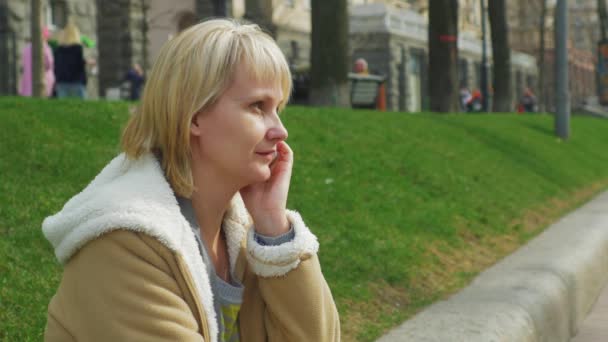 Женщина говорит по телефону в городском парке — стоковое видео