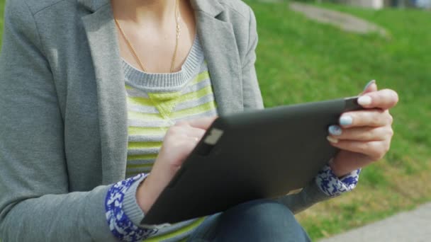 Uma mulher com um tablet no parque — Vídeo de Stock