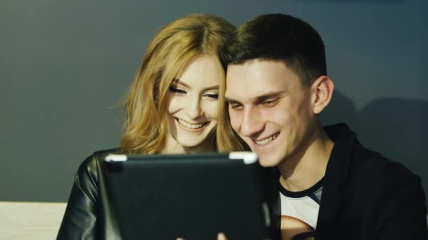 Jong koppel 20-25 jaar maakt gebruik van de tablet in café — Stockvideo