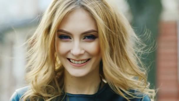 Приваблива жінка, посміхаючись на камеру, грає з волоссям — стокове відео