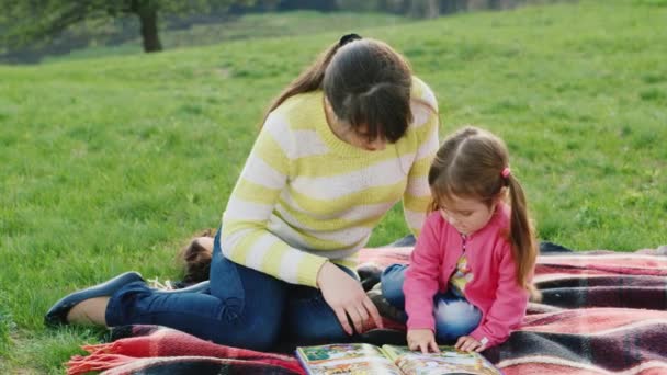 Mamá lee un cuento de hadas hija en el parque — Vídeo de stock