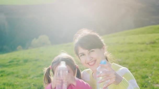 Vrouw met meisje schoon drinkwater op een picknick — Stockvideo