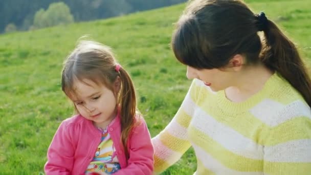 엄마와 딸 애플을 놀고 있다. 공원에 잔디에 앉아 — 비디오