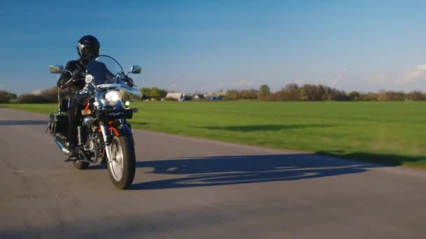 Motorcycle riding on a background of green field and blue sky — Stock Video