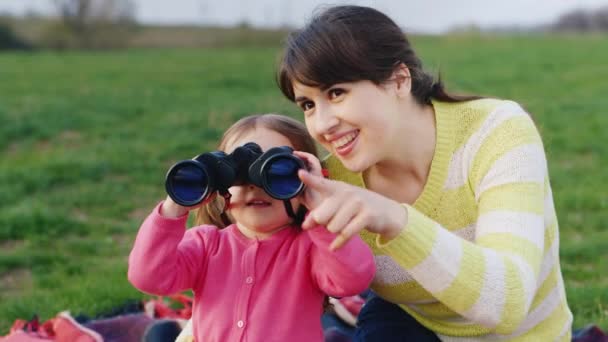 Giovane donna con una ragazza tre anni guardando attraverso il binocolo — Video Stock