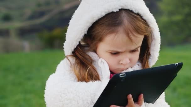 Chica muy seria de 3 años con una tableta — Vídeos de Stock