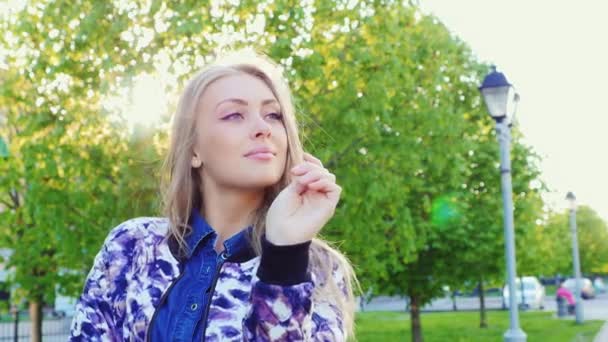 Retrato de una joven en un parque de la ciudad en primavera. Sonrisas y sueños — Vídeos de Stock