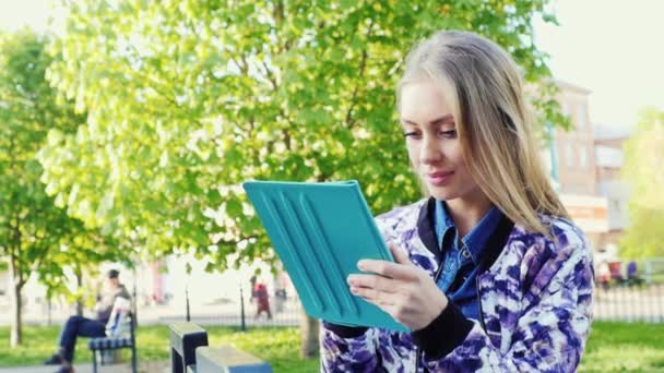 Attraktive Frau genießt die Tablette im Park — Stockvideo