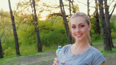 Fitness kadın parkta bir şişe suyu içer