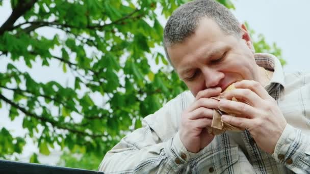 Brutalny mężczyzna w średnim wieku jeść fast foodów na zewnątrz — Wideo stockowe