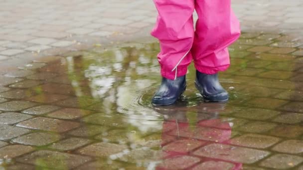 Kinderbeine springen in eine Pfütze — Stockvideo