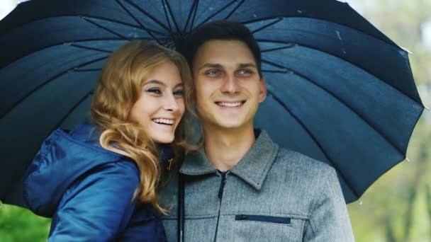 Una joven pareja bajo un paraguas: la lluvia — Vídeo de stock