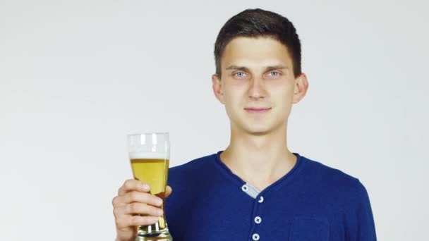 Un joven con un vaso de cerveza sobre un fondo blanco — Vídeos de Stock