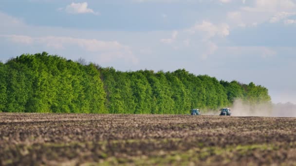 Traktor auf einem Feld pflanzt. im Hintergrund Wald und blauer Himmel — Stockvideo