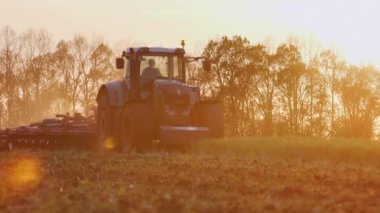 Batan güneşin ışınları bir tarlayı traktör