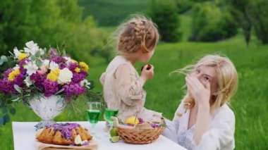 Bir kızı ile gülüyor ve dalga 4 yıl, anne. Bunu bir piknik yeşil çim üzerinde mi