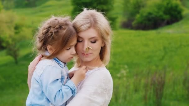 Moeder speelt met haar dochter van 4 jaar. Hij houdt haar in zijn armen op de achtergrond van een groen gazon — Stockvideo