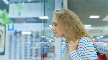Alışveriş torbaları dyal çekici bir kadınla bir dükkanı vitrinlere bakıyor ve sonra kararlı markete gider