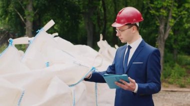 Kask ve takım elbise tutan ürün mühendisi büyük torbalarda denetimleri