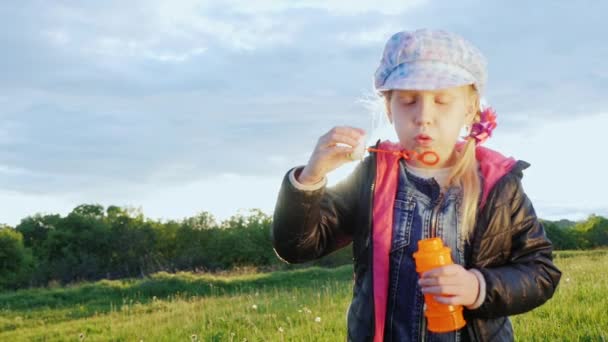 Menina engraçada no boné soprando bolhas — Vídeo de Stock