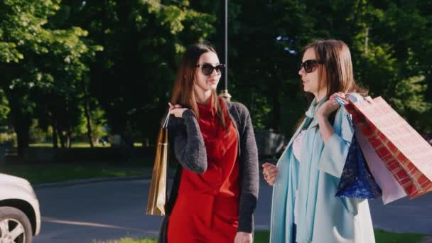 Zwei Freundinnen mit Einkaufstüten, die sich im Freien unterhalten — Stockvideo