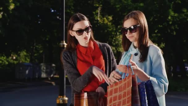 Deux jeunes femmes après une expérience d'achat réussie. Ils se montrent leurs achats — Video