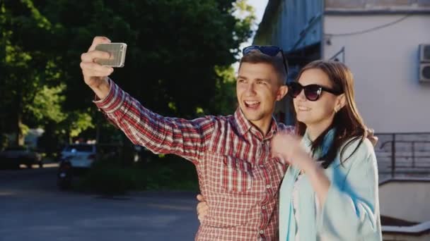 Een liefdevolle paar maakt selfie. In de stralen van de zon buitenshuis — Stockvideo
