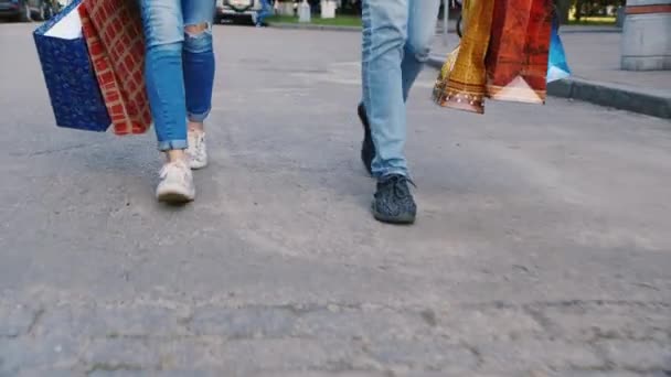 Homme et femme sont sur le trottoir avec des sacs à provisions dans l'image ne peut être vu que les jambes — Video