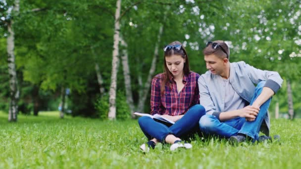 Přátelé-studenti čtou knihu v parku — Stock video